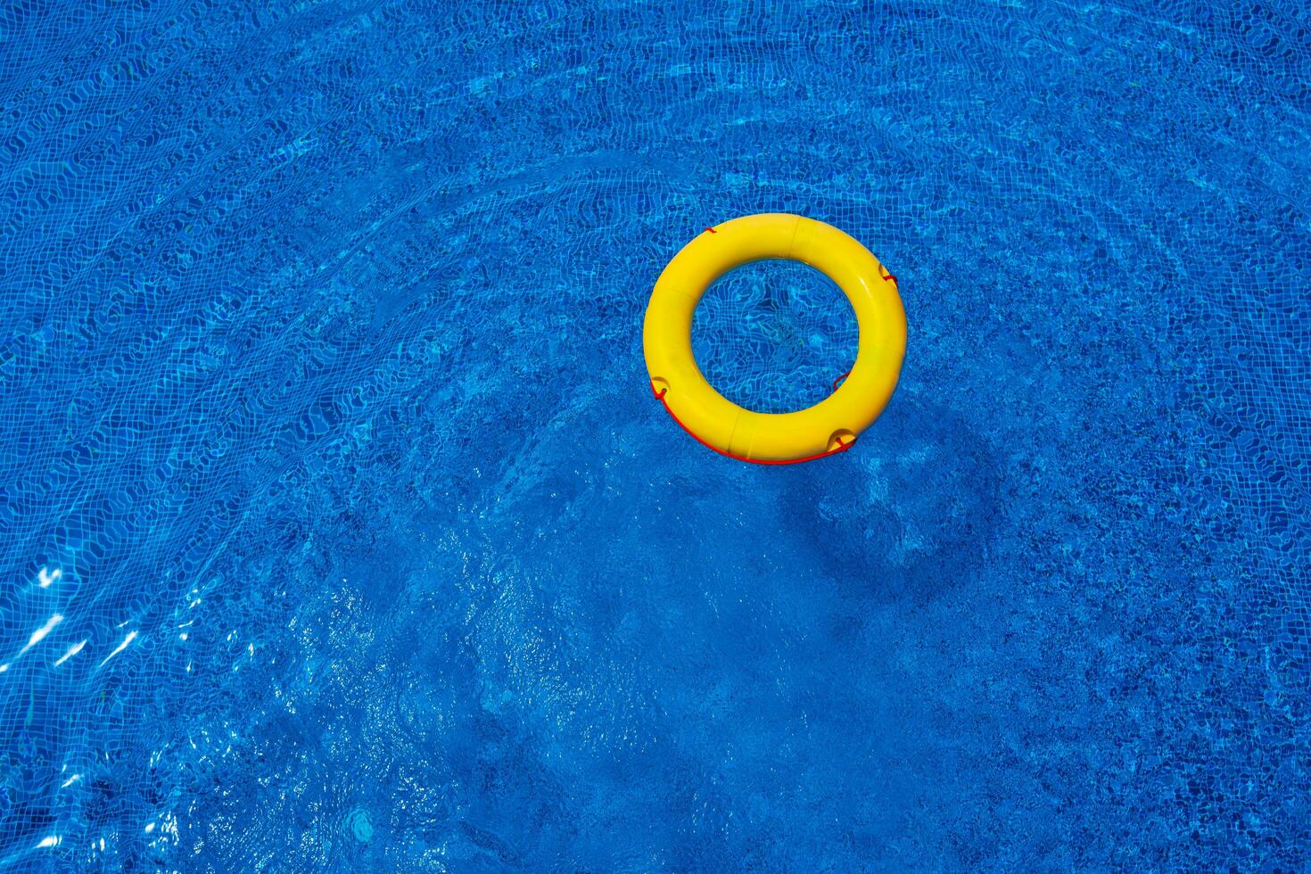 Top view of lifebuoy floating in blue swimming pool, soft focus. photo