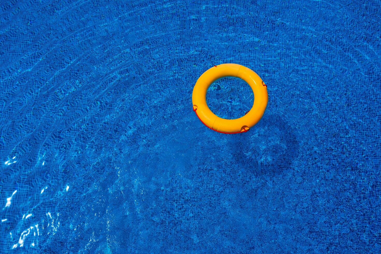 Top view of lifebuoy floating in blue swimming pool, soft focus. photo