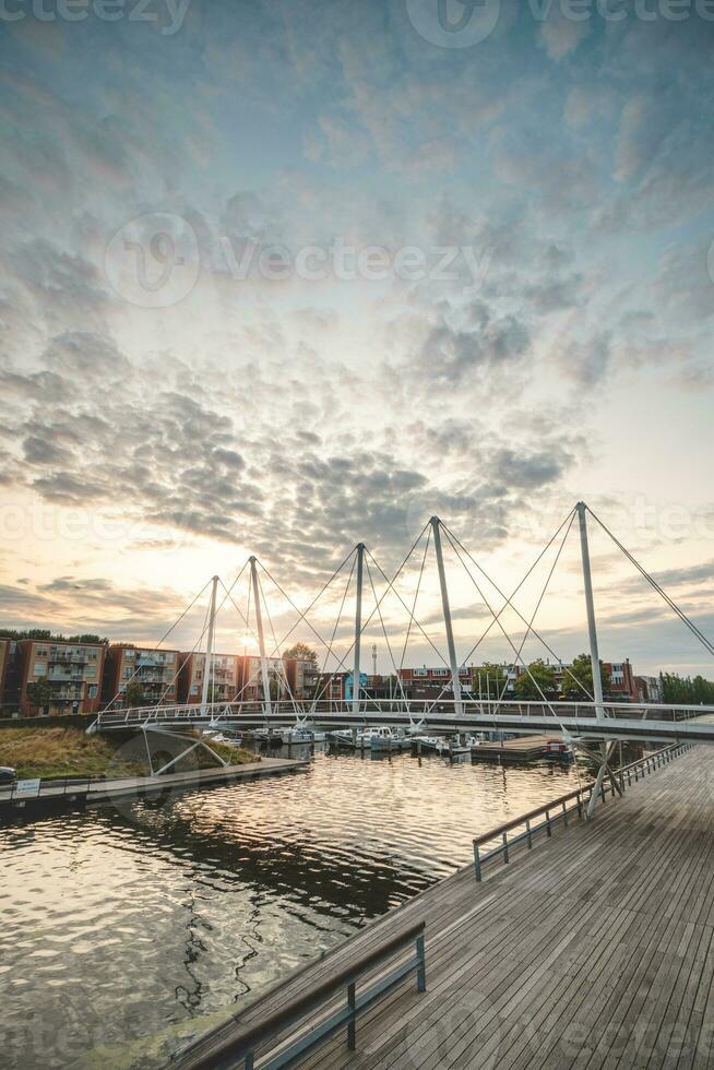 Pedestrian and bicycle bridge over the harbour in the centre of Almere during sunset. Dutch modern and utilitarian construction photo