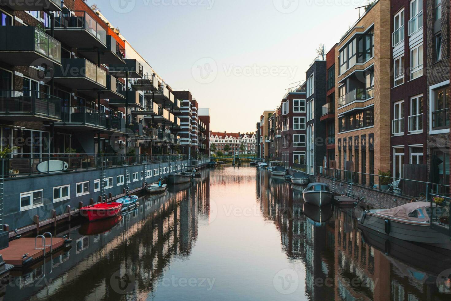 Colourful apartment blocks reflecting on the water surface of the canal that crosses the buildings. Dutch housing. House lifestyle photo