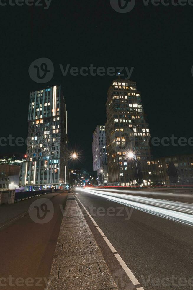 Nightlife on the streets of Rotterdam, Netherlands. Passing cars and skyscrapers photo