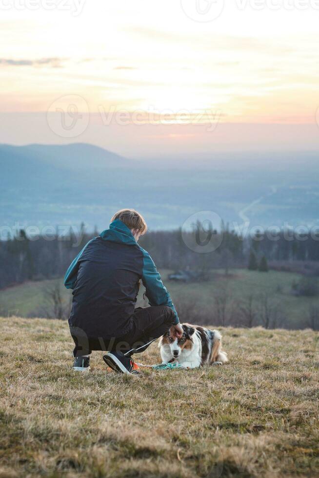 Young cynologist, a dog trainer trains a four-legged pet Australian Shepherd in basic commands using treats. Love between dog and human photo