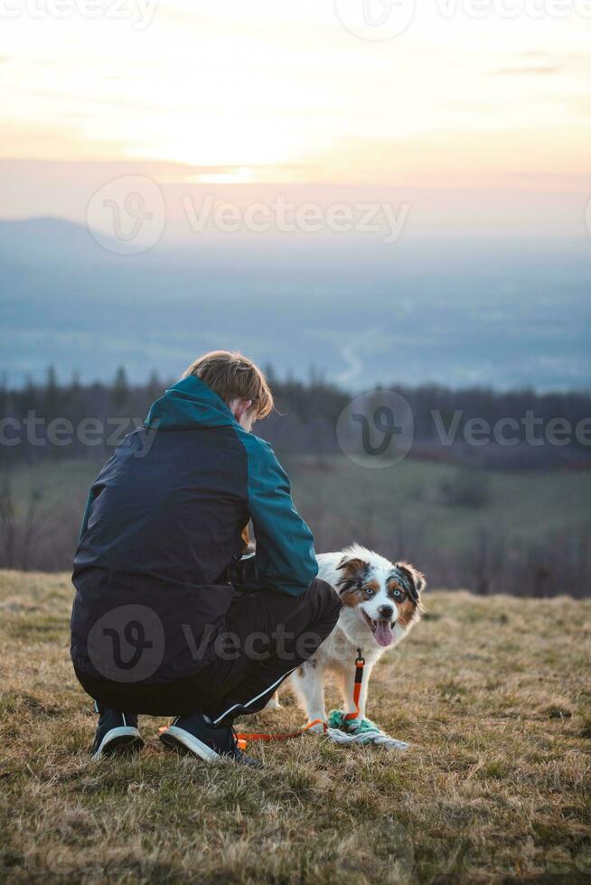 Young cynologist, a dog trainer trains a four-legged pet Australian Shepherd in basic commands using treats. Love between dog and human photo