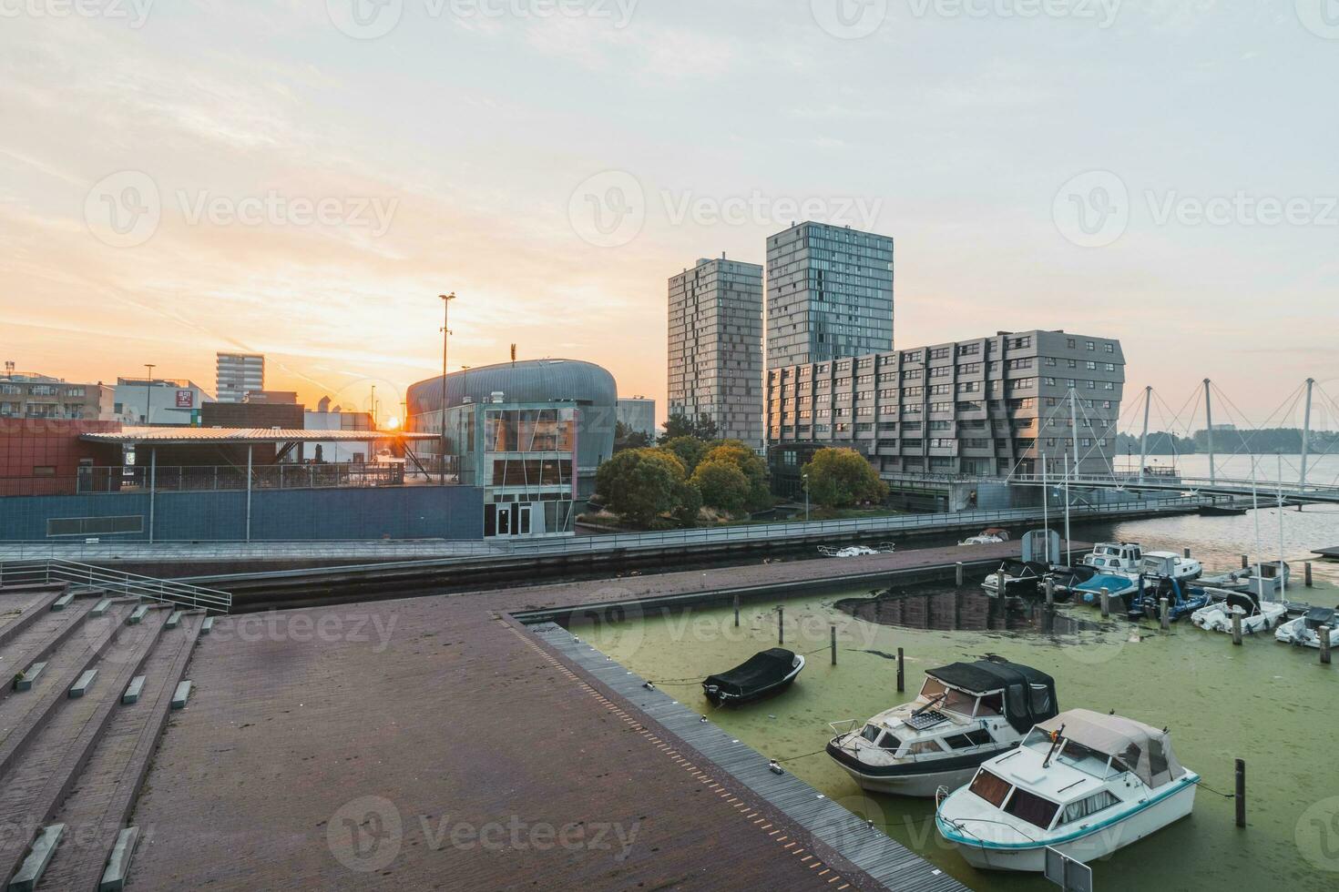 Waking harbour with ships in Almere, Netherlands. City centre in the morning sunlight. Red-pink sky photo