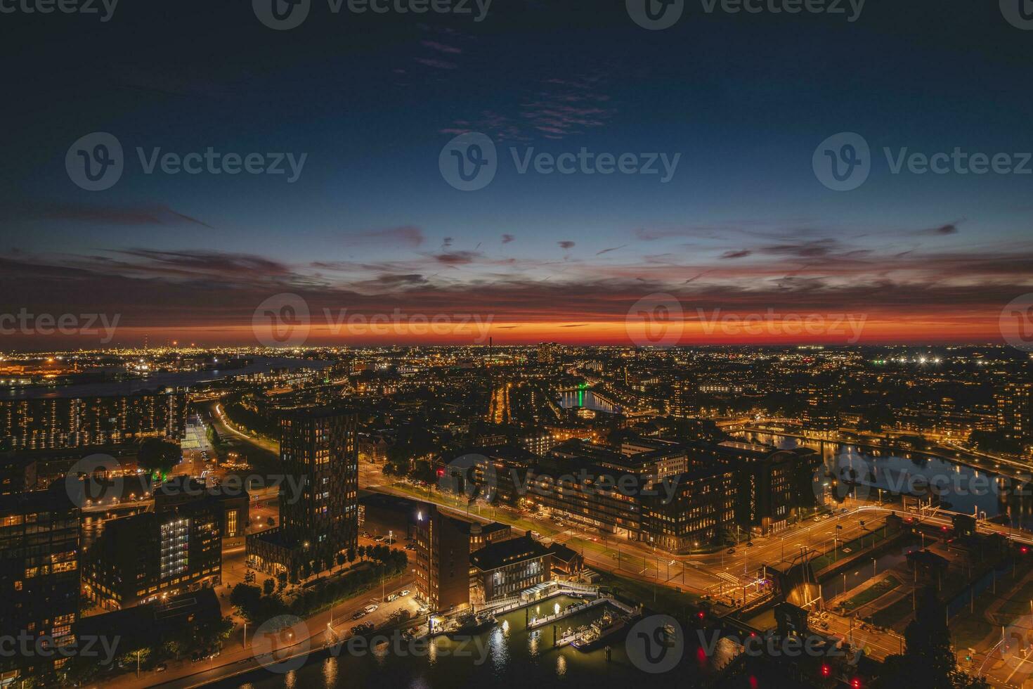 Aerial view of nightlife in the modern city of Rotterdam in the Netherlands. Red glow from the setting sun in the background photo