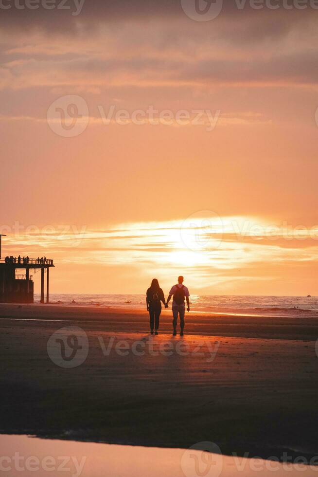 Romantic walk of a young couple on the beaches of Oostende in western Belgium at sunset. Love and devotion. Reflection in a pool of water photo