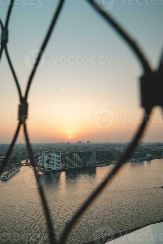 capital de el Países Bajos, Amsterdam debajo el último rayos de día. el ciudad centrar y ferrocarril estación durante puesta de sol foto