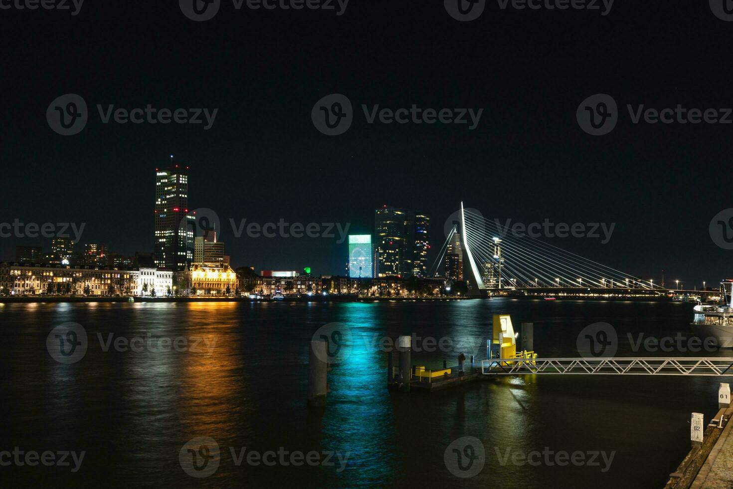 View of the canal and the opposite illuminated bank with lots of illuminated skyscrapers during late night in Rotterdam, Netherlands photo