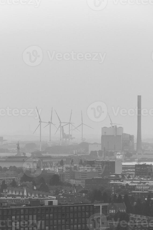 Smog hovering over the city of Amsterdam in black and white format. In the distance, the change in energy availability within wind farms photo