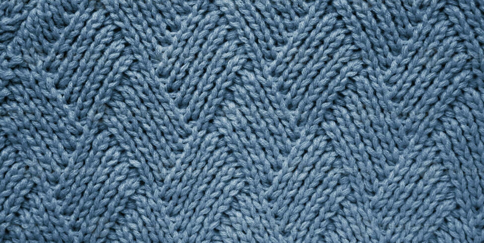 The texture of a knitted woolen fabric into a rhombus blue gray color. Abstract background. Wallpaper. Banner. Close-up. Selective focus. photo