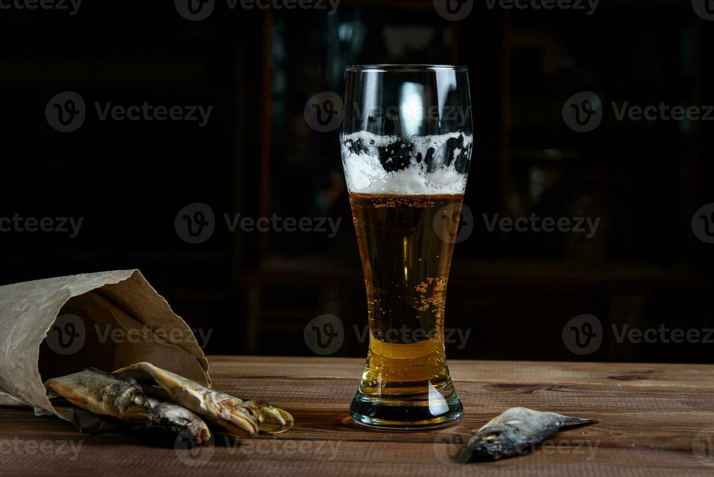Glass of beer and dried fish on a wooden table photo