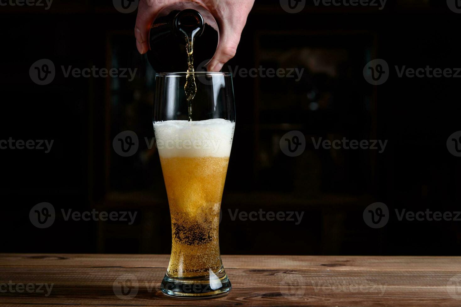 Glass with beer on a wooden table. Beer is poured into a glass from a bottle. photo