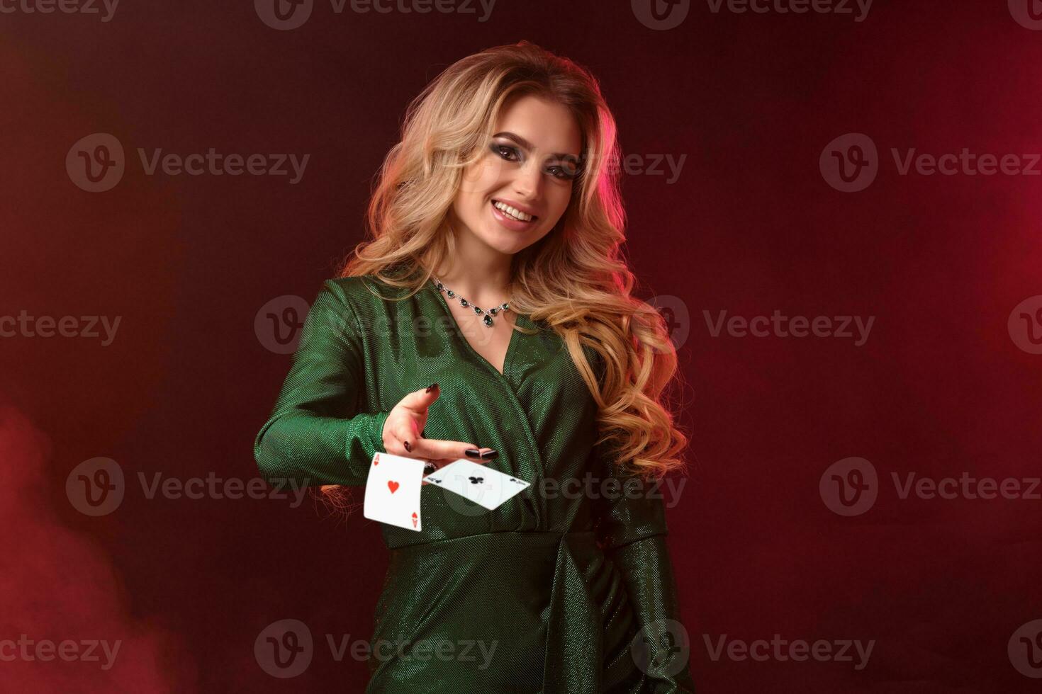 rubia niña en verde elegante vestir y joyas. ella es sonriente y alcanzando su mano a tú, posando en contra vistoso ahumado antecedentes. de cerca. foto