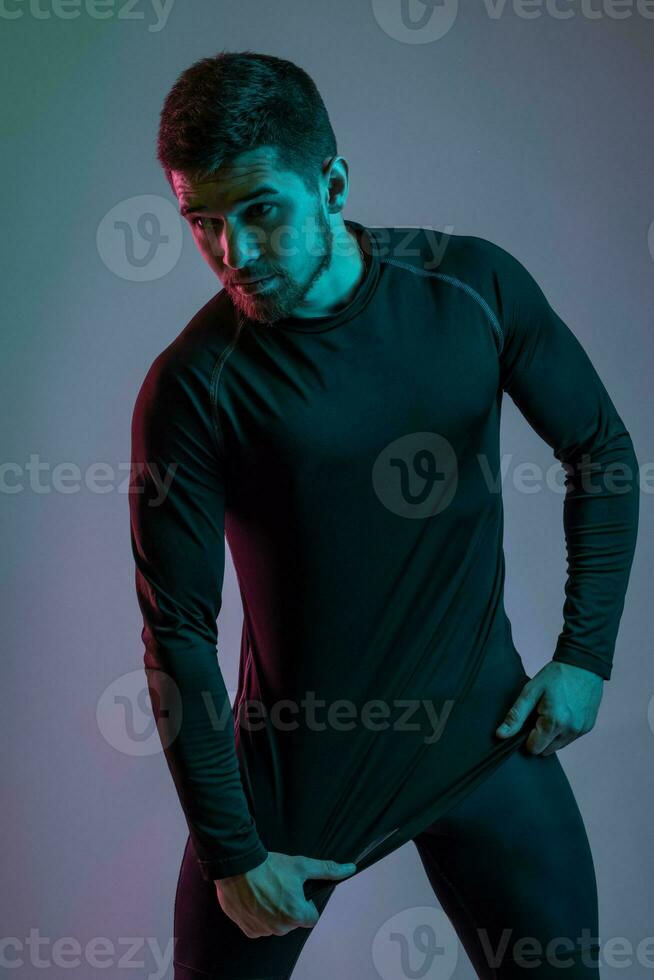 Guy in black sportswear posing in studio on grey background photo