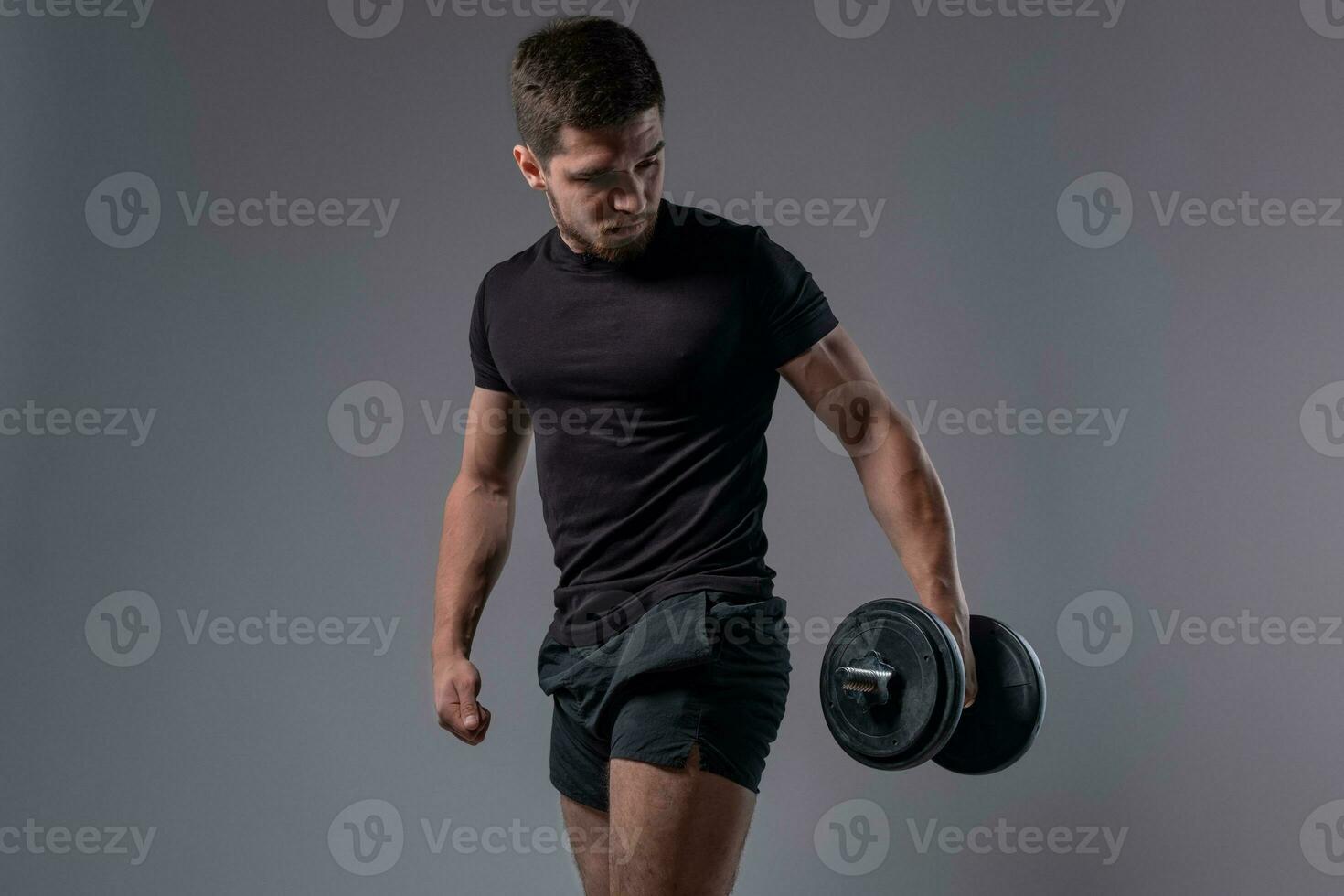 Young athletic man during weight training with dumbbells photo