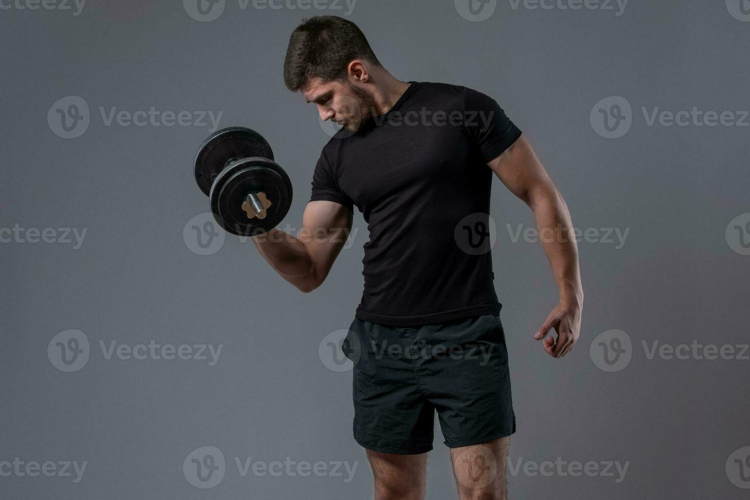 Sporty guy performing biceps curl with dumbbell photo