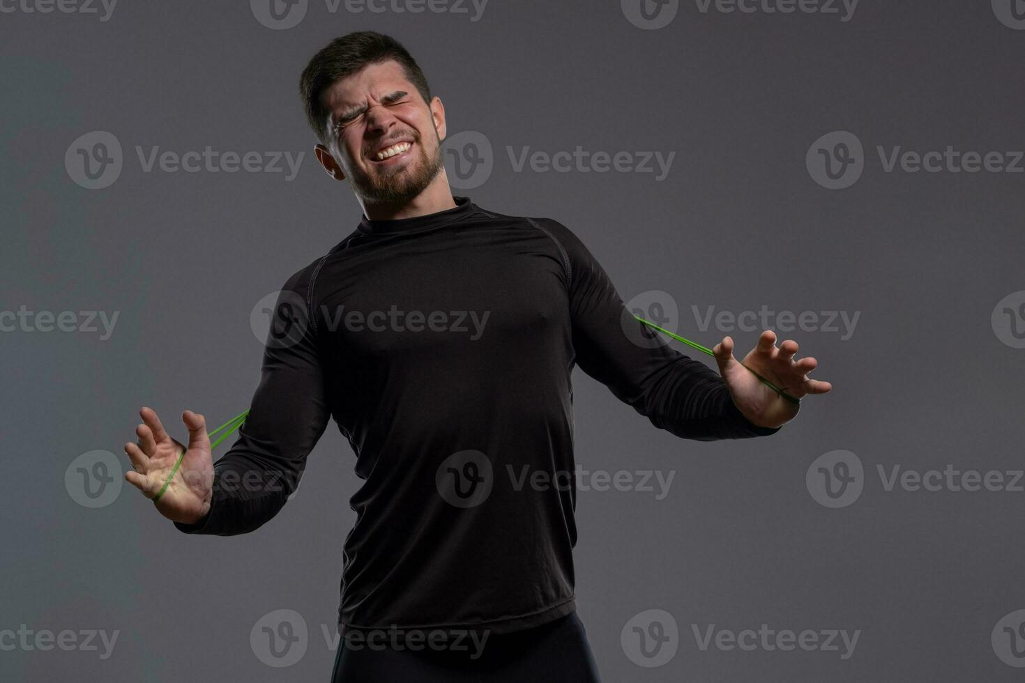 Emotional young sportsman stretching resistance band with hands photo