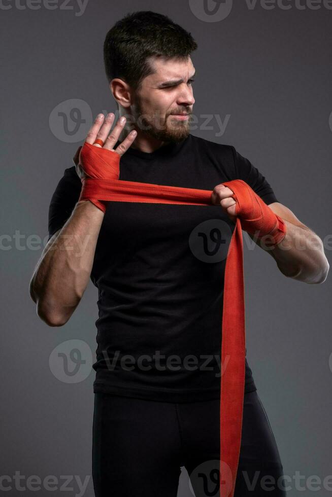 Young mixed martial artist putting on hand wraps photo