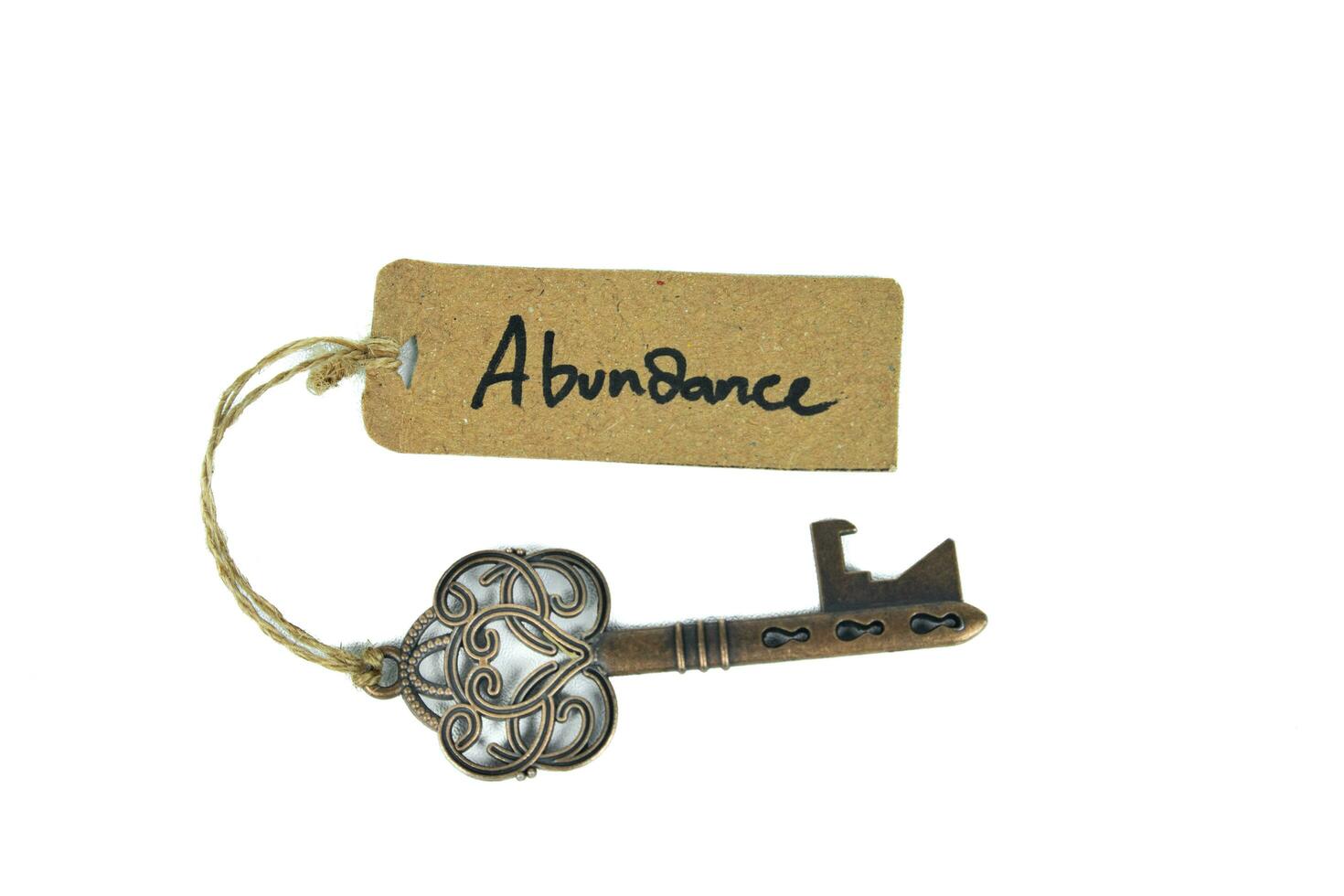 Key to abundant life concept - Old key with abundance tag isolated on white background photo