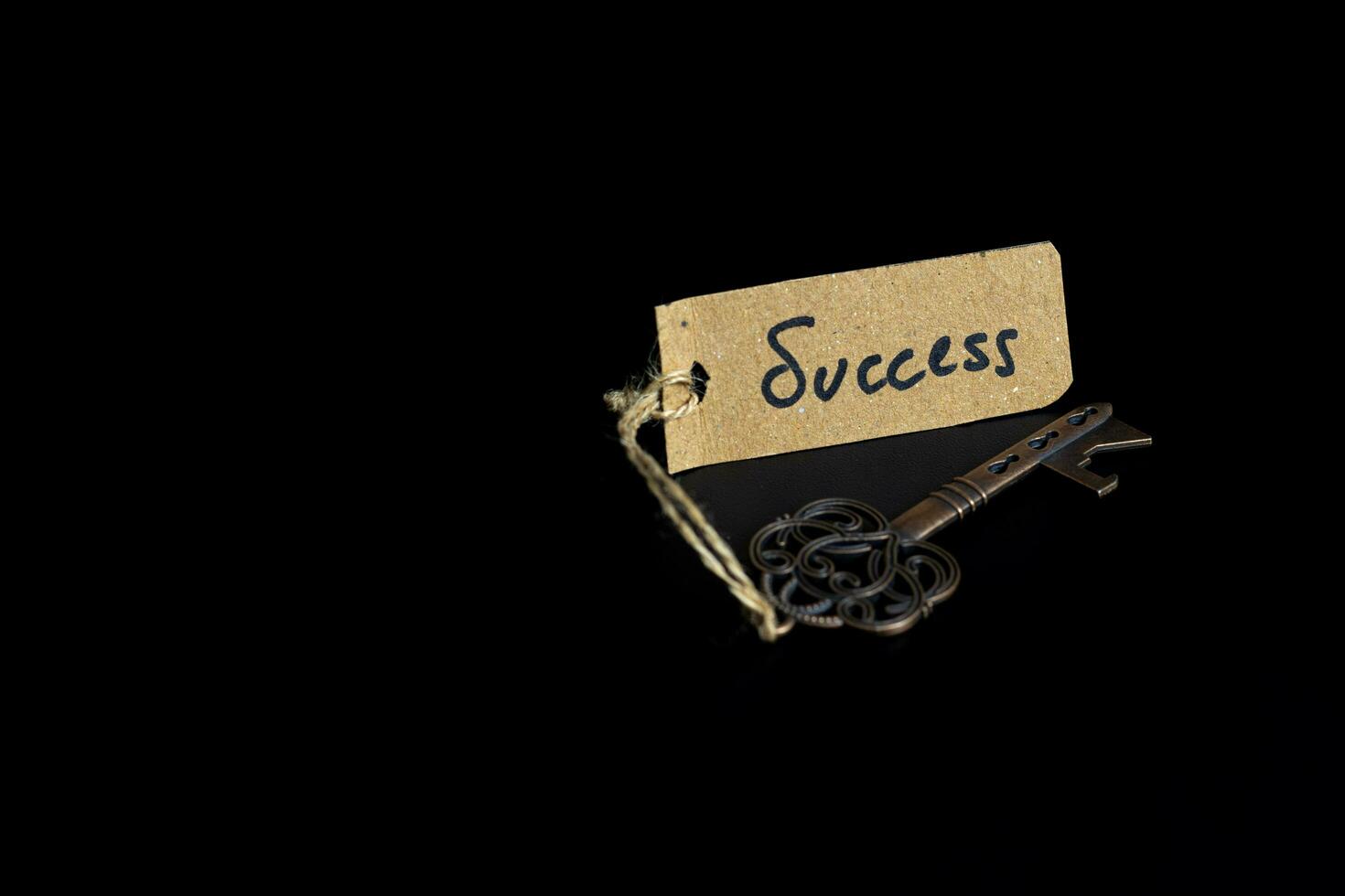 Key to Success concept - Old key with success tag isolated on black background photo