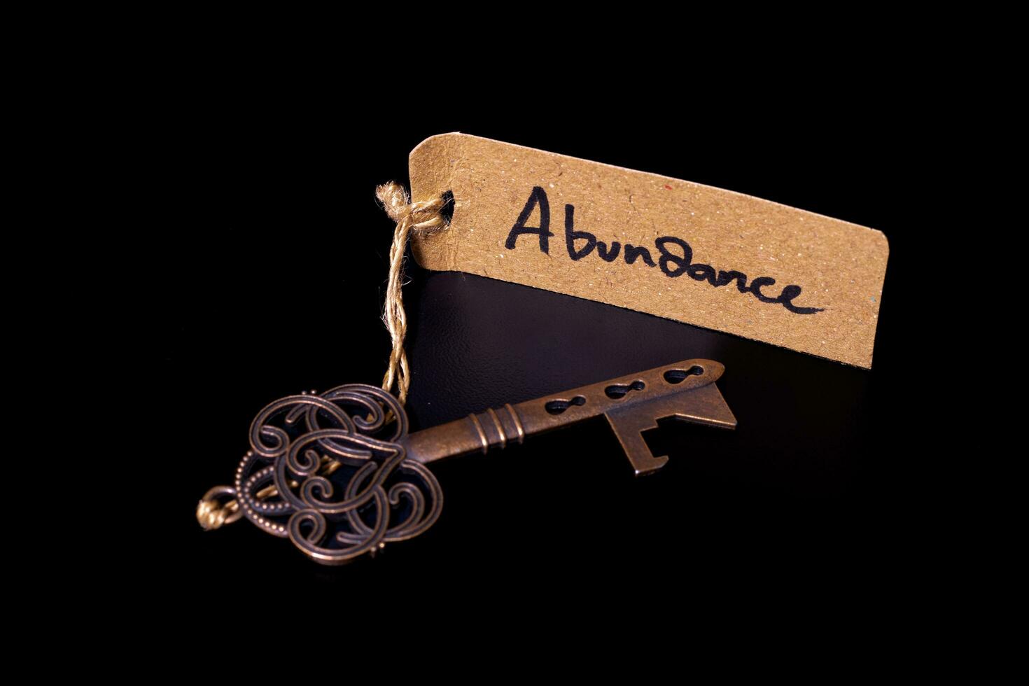 Key to abundant life concept - Old key with abundance tag isolated on black background photo