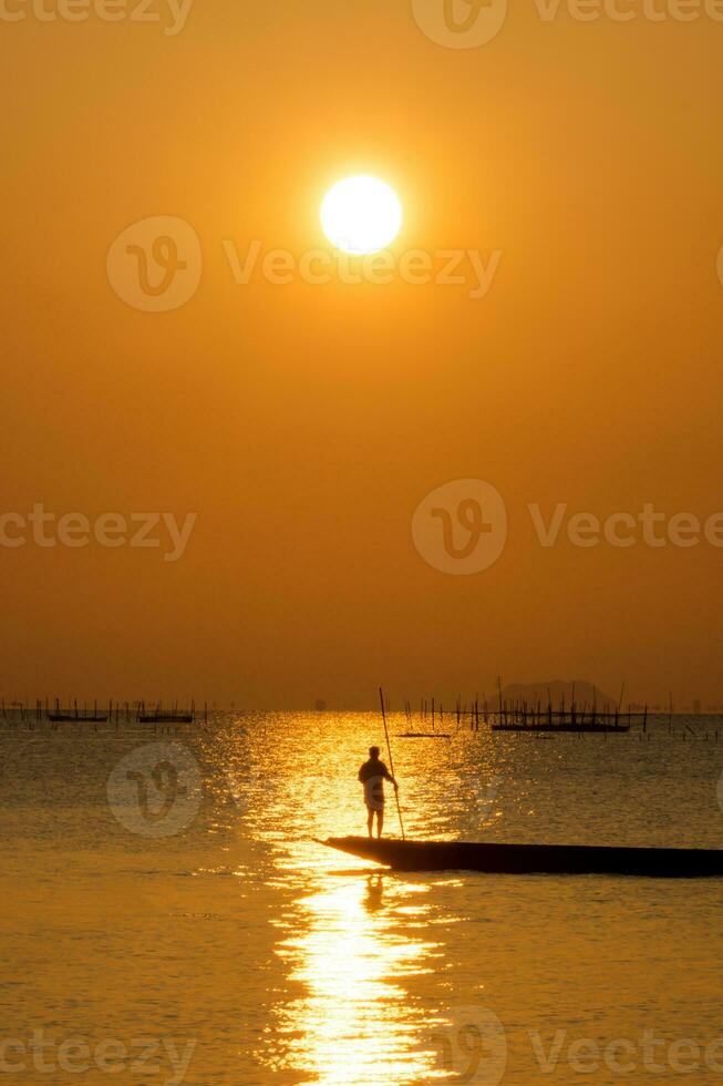 Silhouette fisherman with sunset sky on the lake in south of Thailand. photo