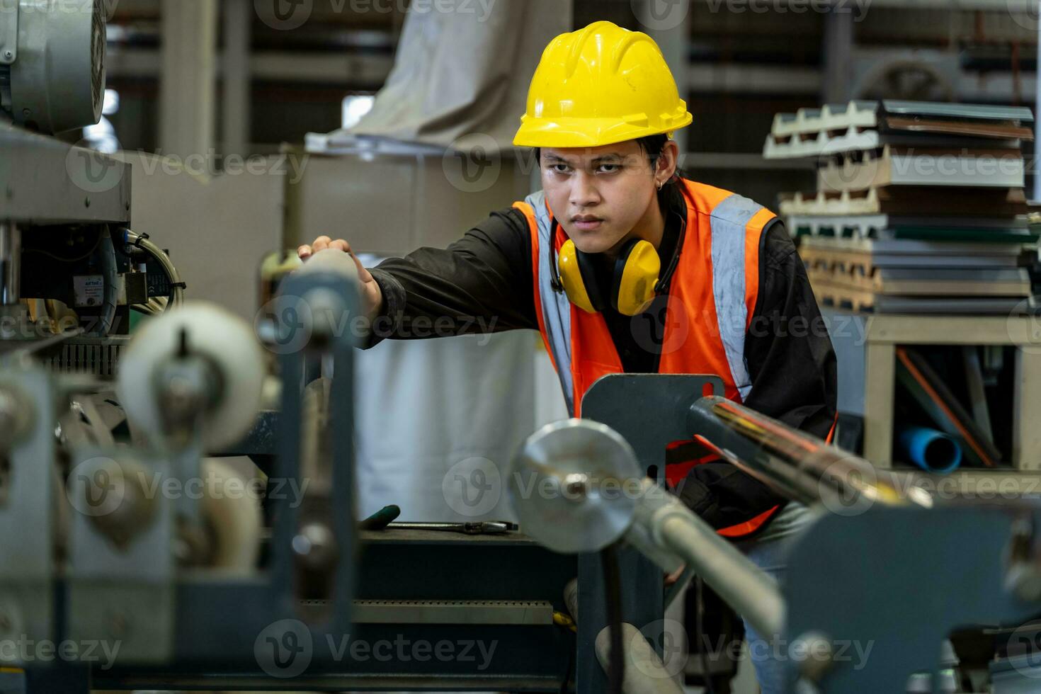 Asian industrial worker is checking the setup value of metal sheet roll forming machine inside roof factory for safety industry construction photo