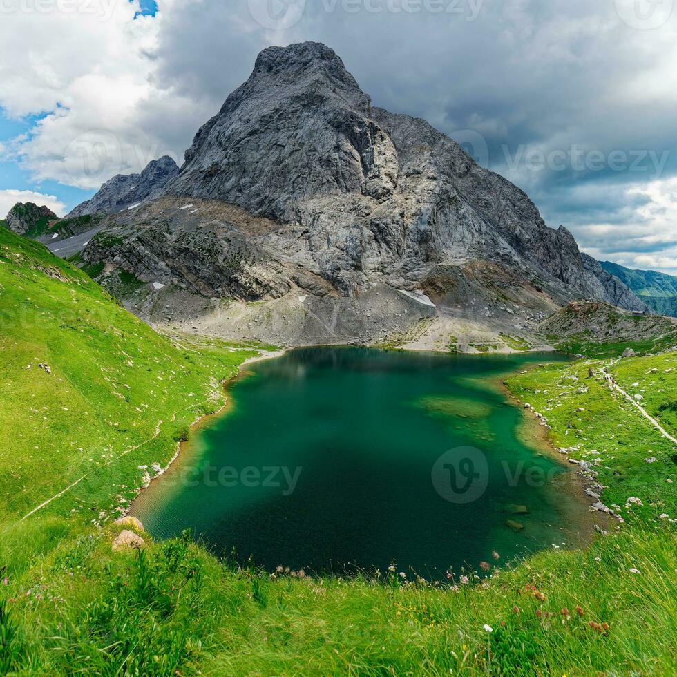 ver de volaya lago, wolayersee, en el frontera de Italia y Austria con coglianos montaña en el antecedentes. nublado día con algunos Dom apertura. vibrante colores. hermosa destinos para caminantes. foto