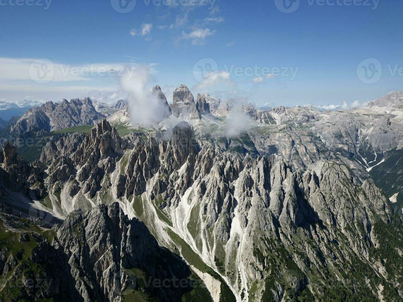 Aerial view of Cadini di Misurina mountains with Tre Cime di Lavaredo mountains in the background during a sunny day with some clouds. Dolomites, Italy. Dramatic and cinematic landscape. photo