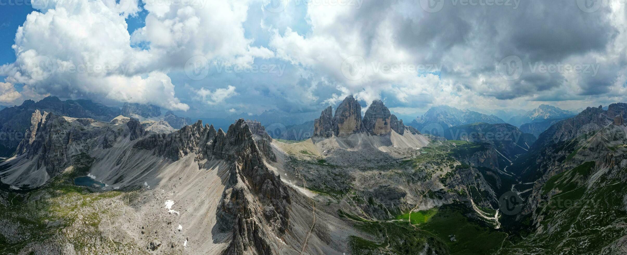 Aerial panoramic view of Tre Cime di Lavaredo mountain during a sunny day with clouds and fog in the Dolomites, Italy. Dramatic and cinematic landscape. very famous places for hiking and rock climbing photo