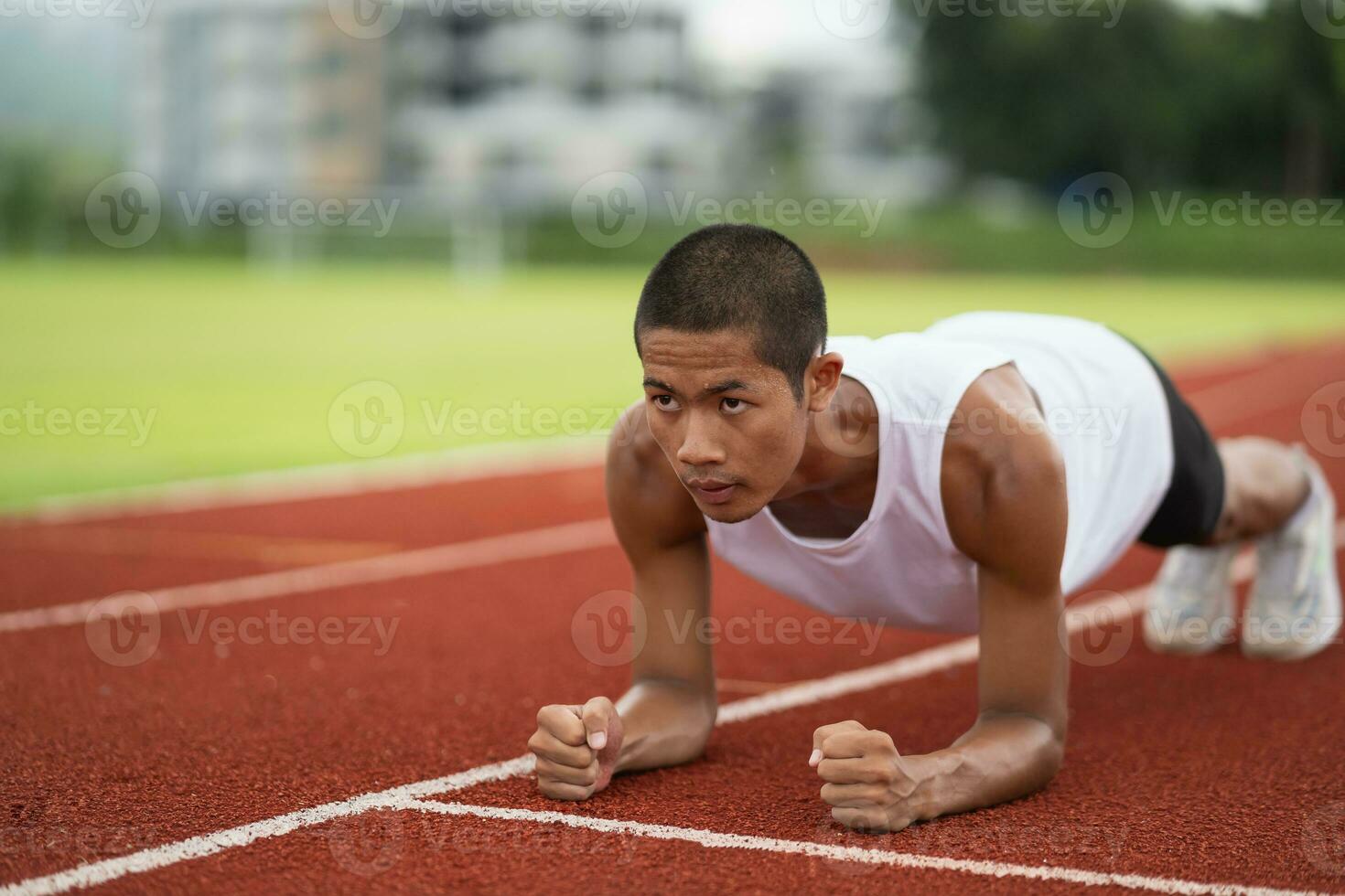 Athletes sport man runner wearing white sportswear to planking stretching and warm up before practicing on a running track at a stadium. Runner sport concept. photo