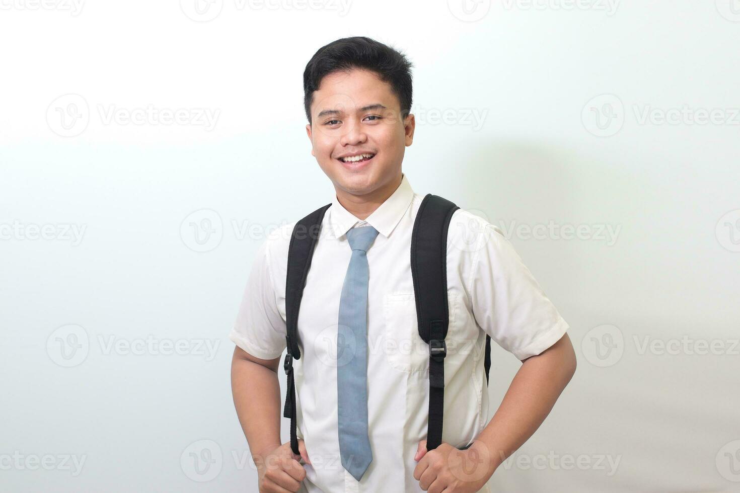 indonesio mayor alto colegio estudiante vistiendo blanco camisa uniforme con gris Corbata sonriente y mirando a cámara. aislado imagen en blanco antecedentes foto