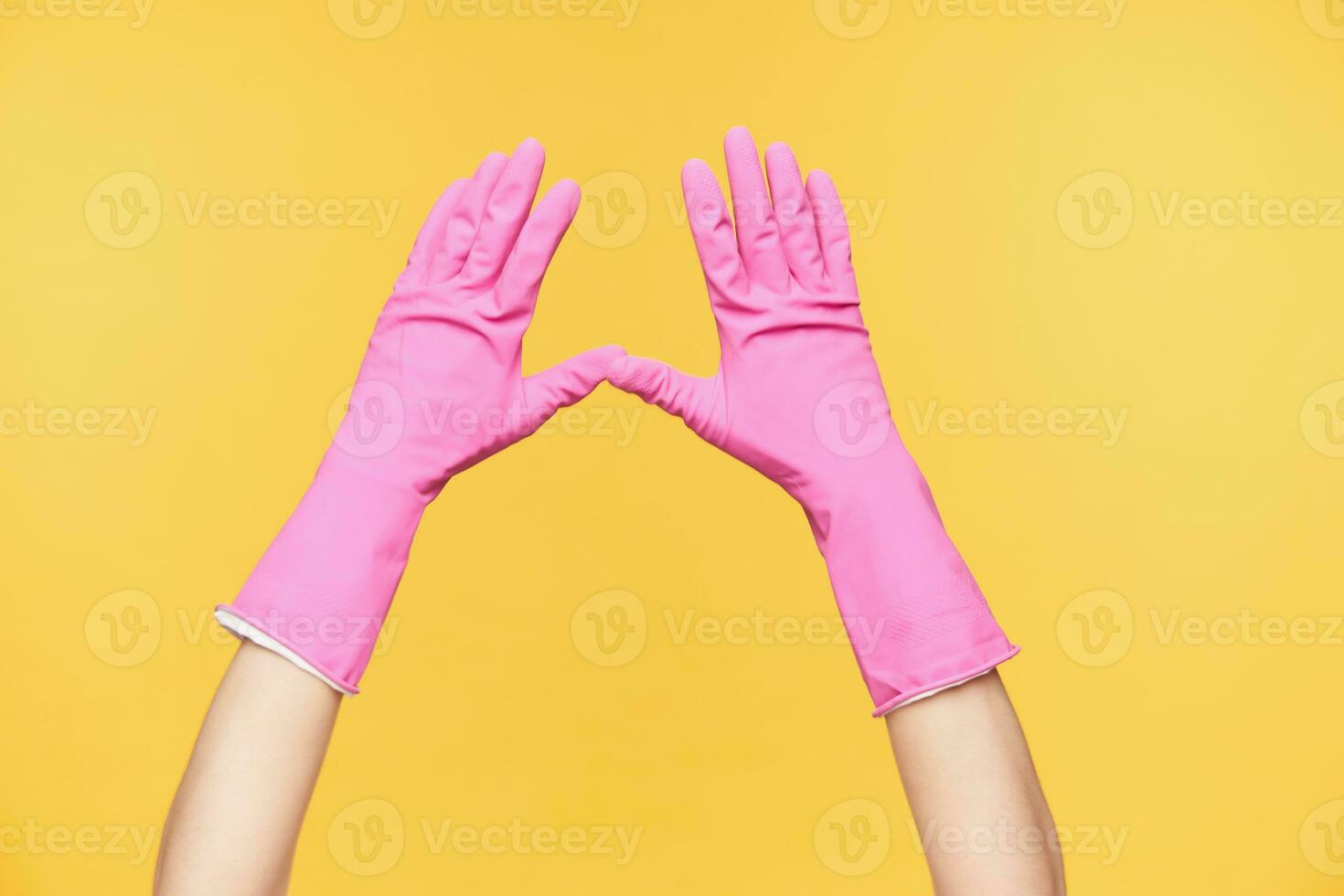 horizontal foto de dos manos en rosado guantes siendo elevado mientras posando terminado naranja fondo, acuerdo pulgares juntos. cuerpo idioma y firmar concepto