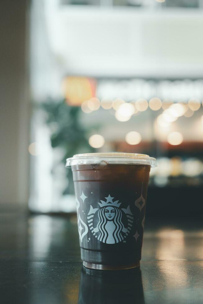 Bangkok, Thailand - December 7, 2023 A takeaway plastic glass with iced Americano black coffee with lid. photo