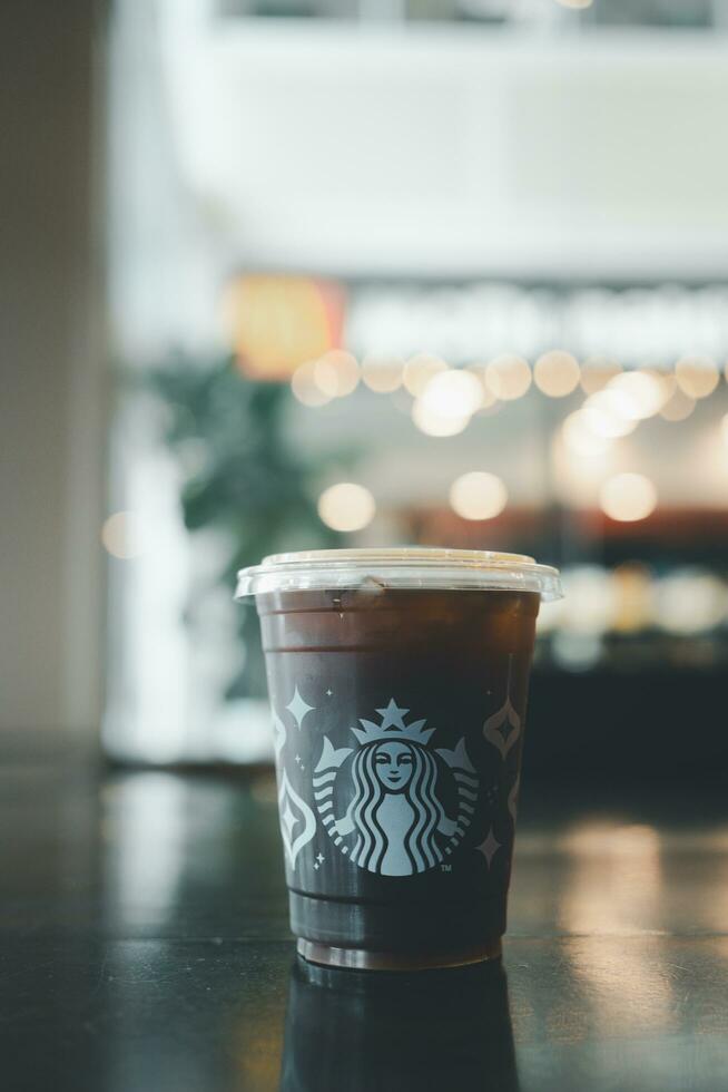 Bangkok, Thailand - December 7, 2023 A takeaway plastic glass with iced Americano black coffee with lid. photo