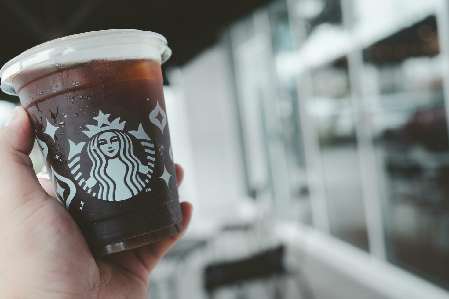 Bangkok, Thailand - December 5, 2023 Hand holding a cold brew coffee in Starbucks coffee shop. photo