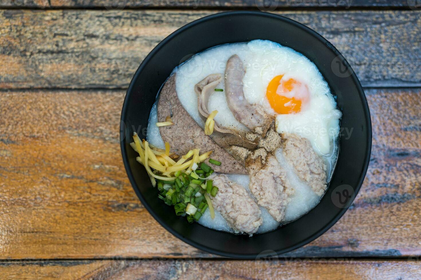 Congee with soft boiled egg and pork liver, pork intestines, ginger sliced, spring onion sliced, coriander sliced. photo