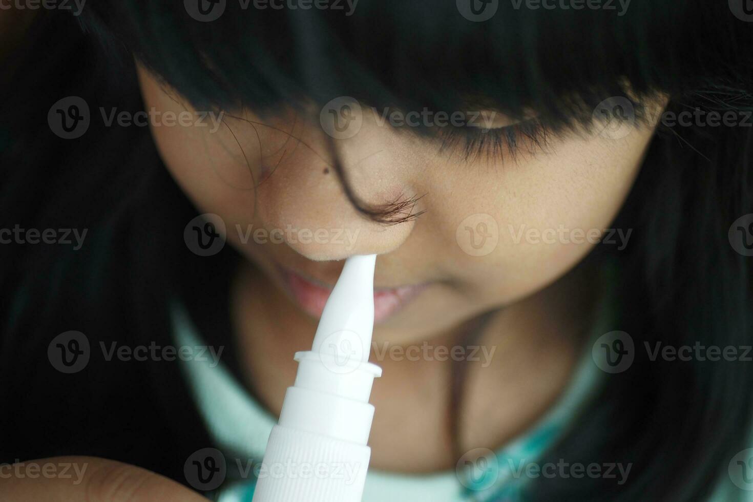 close up of sick child using nasal medicine spray photo