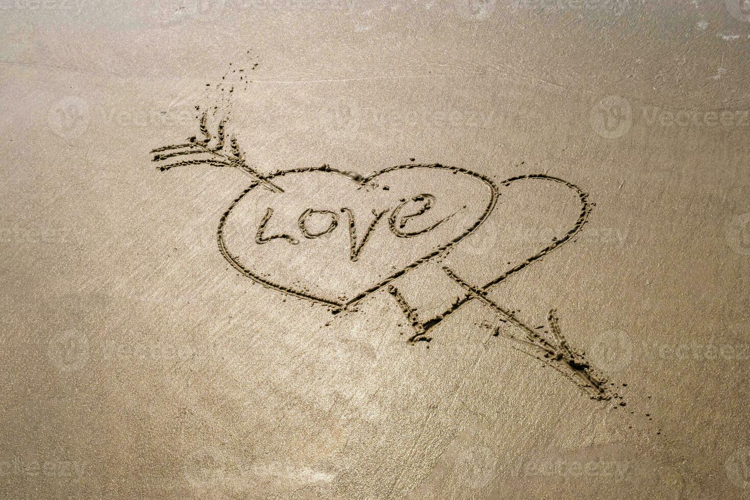 drawing in sand in form of two hearts and inscription love photo