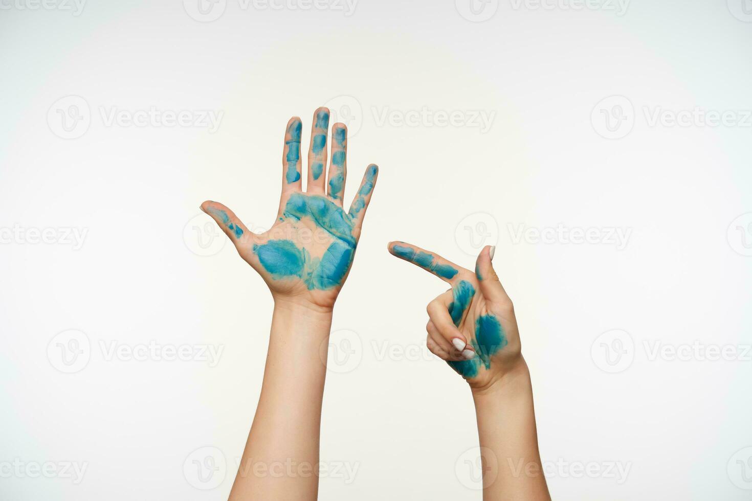 Studio photo of raised painted pretty lady's fair-skinned hands posing over white background, one hand is showing on another with index finger