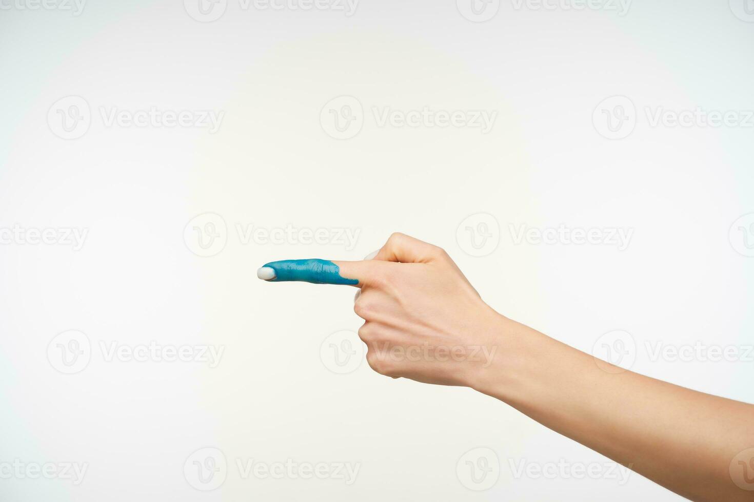 Cropped shot of young woman's hand with white manicure keeping forefinger raised while pointing aside, isolated over white background. Human body concept photo