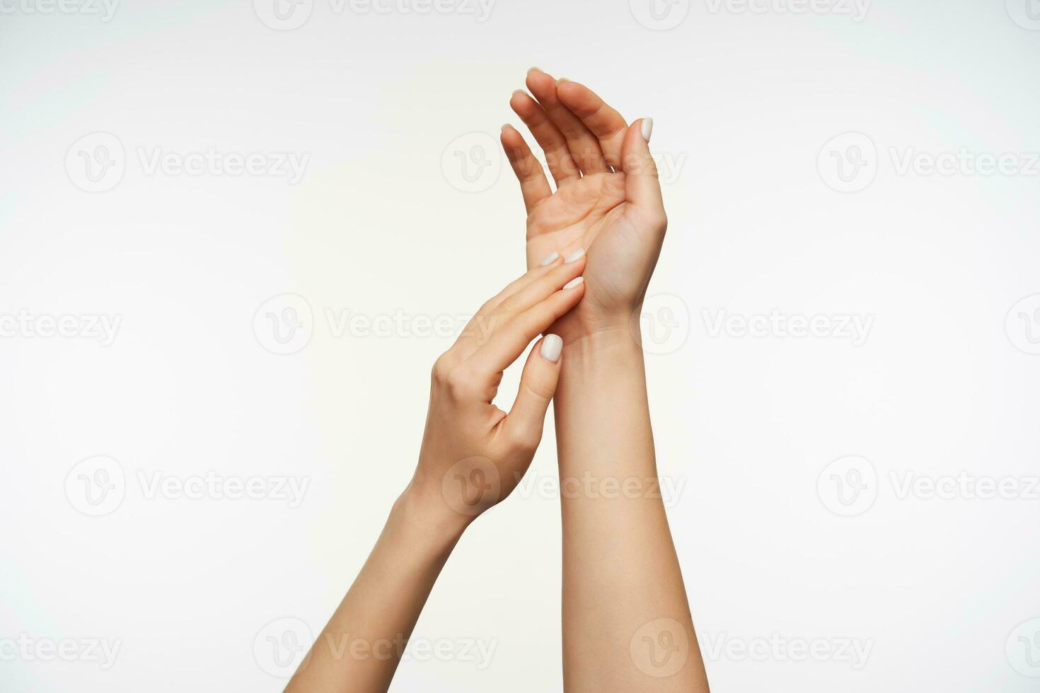 Close-up of pretty lady's hands touching gentle each others while posing over white background, keeping hands raised while lathering hands photo