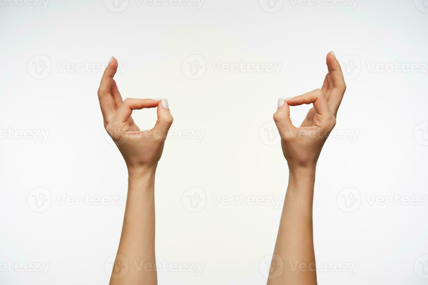 Indoor photo of young lady's hands with white manicure forming murda gesture while posing over white background. Women showing hand with sign language