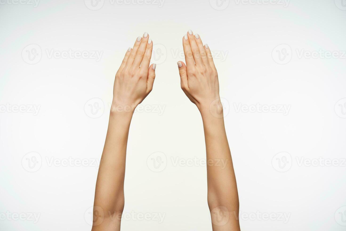 Close-up of beautiful woman's hand with manicure keeping fingers together while posing against white background, hand symbol viewed from back photo