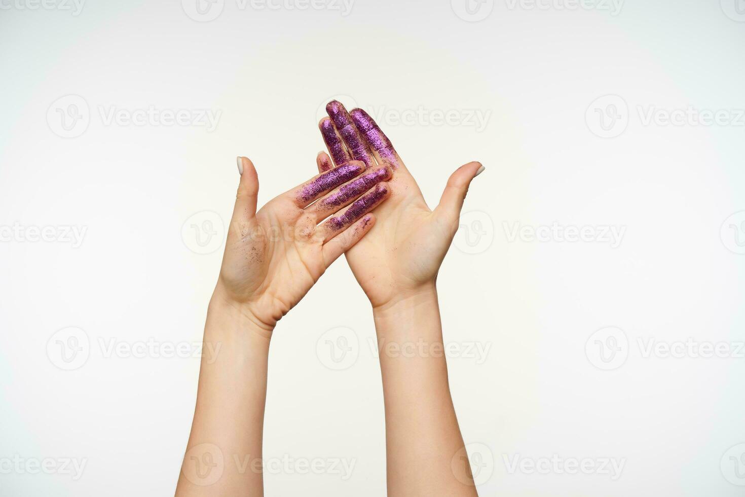 Front view of young fair-skinned pretty hands showing palms with violet sparkles while posing standing isolated over white background. Human hands and gesturing concept photo
