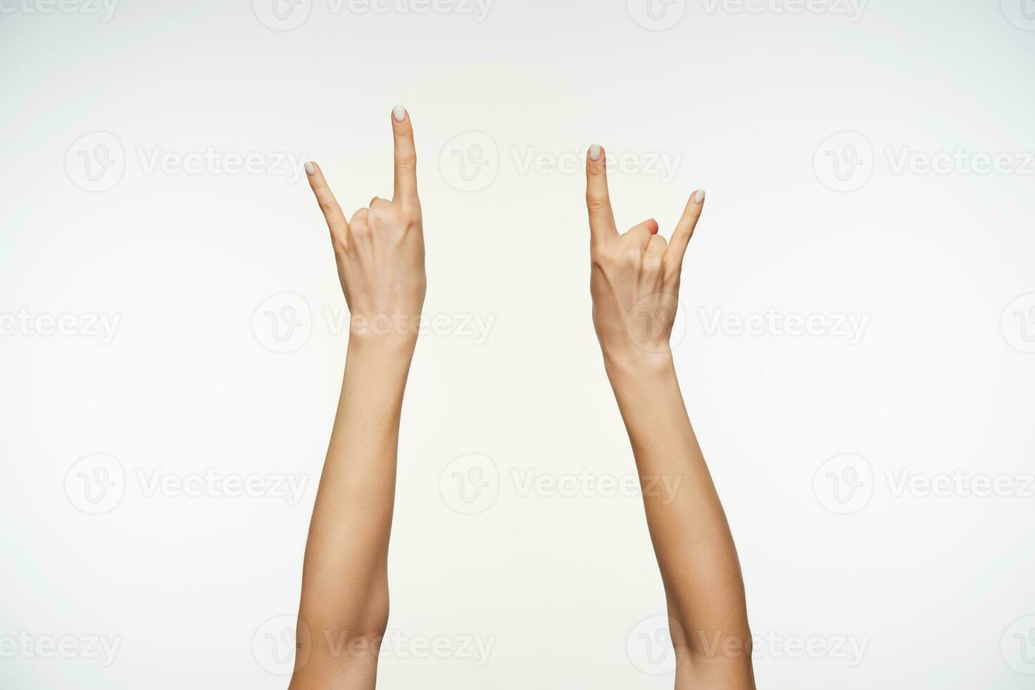 Indoor shot of attractive females's hands raised against white background, forming with fingers love sign. Women showing hand with sign language photo