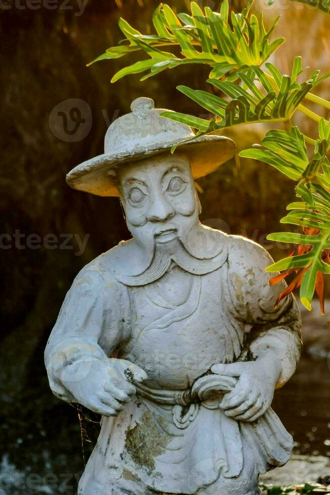 un estatua de un hombre con un sombrero y un planta foto