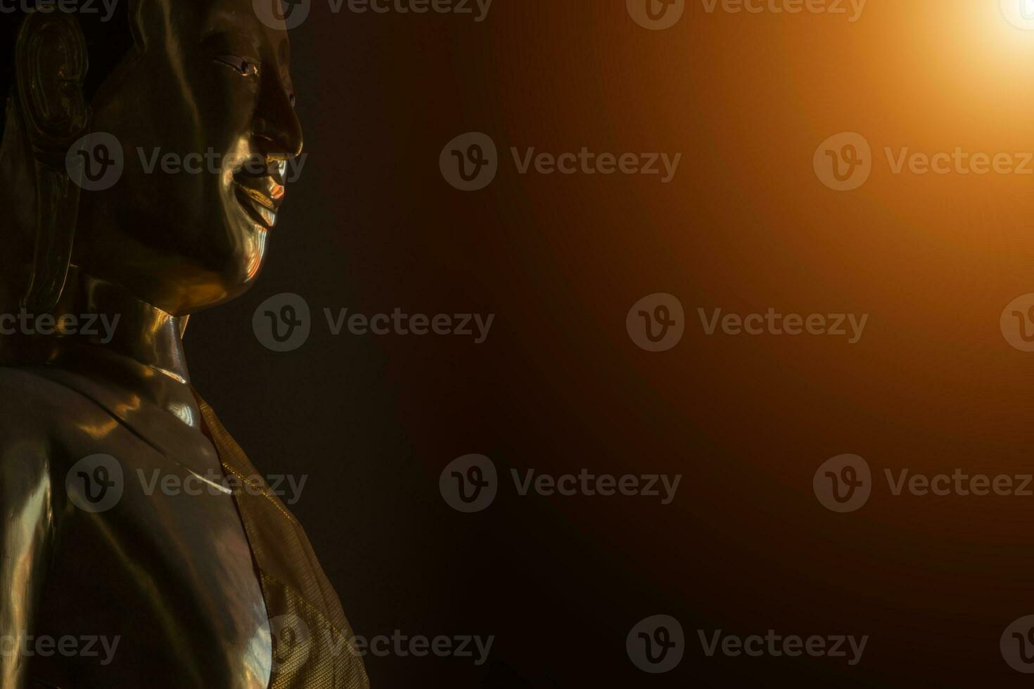 Portrait of a golden Buddha statue in the dark rooms with sunlight photo