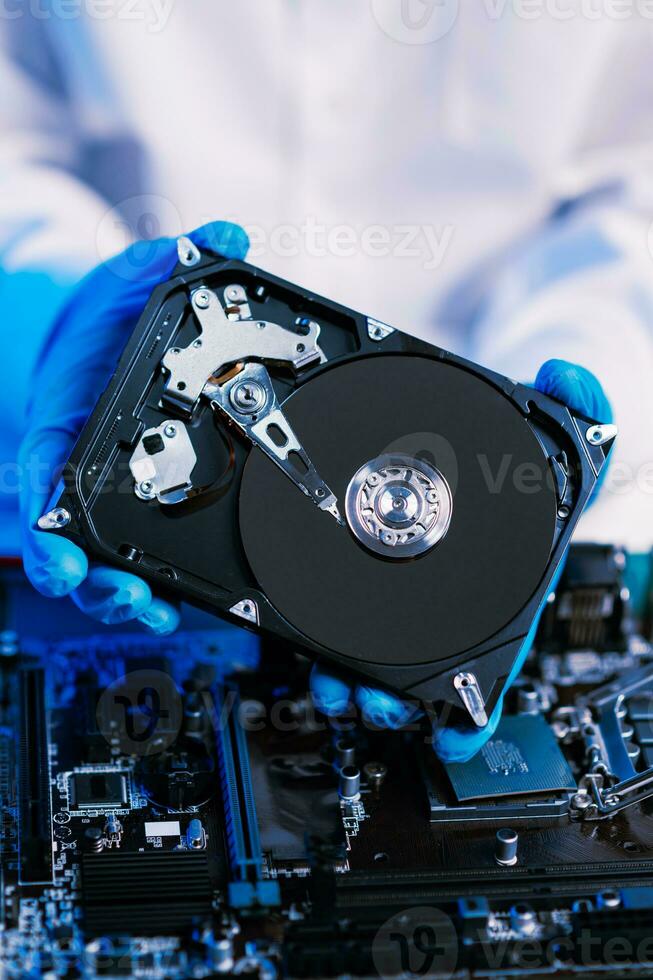 Hard disk drive on the technician's desk and a computer motherboard as a component. the concept of data, hardware, and information technology. photo