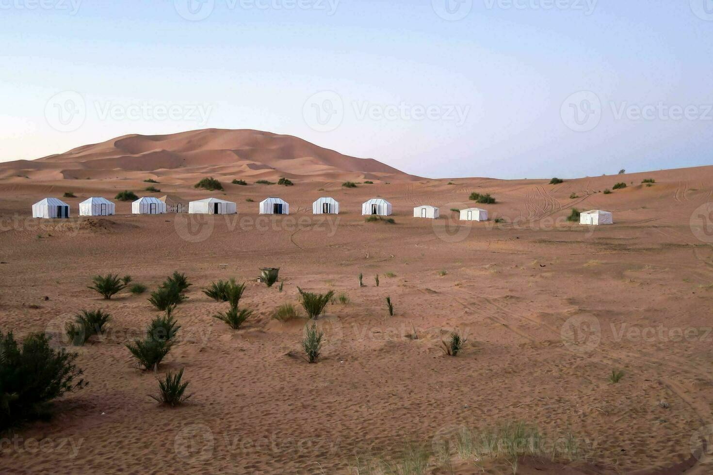 a group of tents in the desert with sand dunes photo